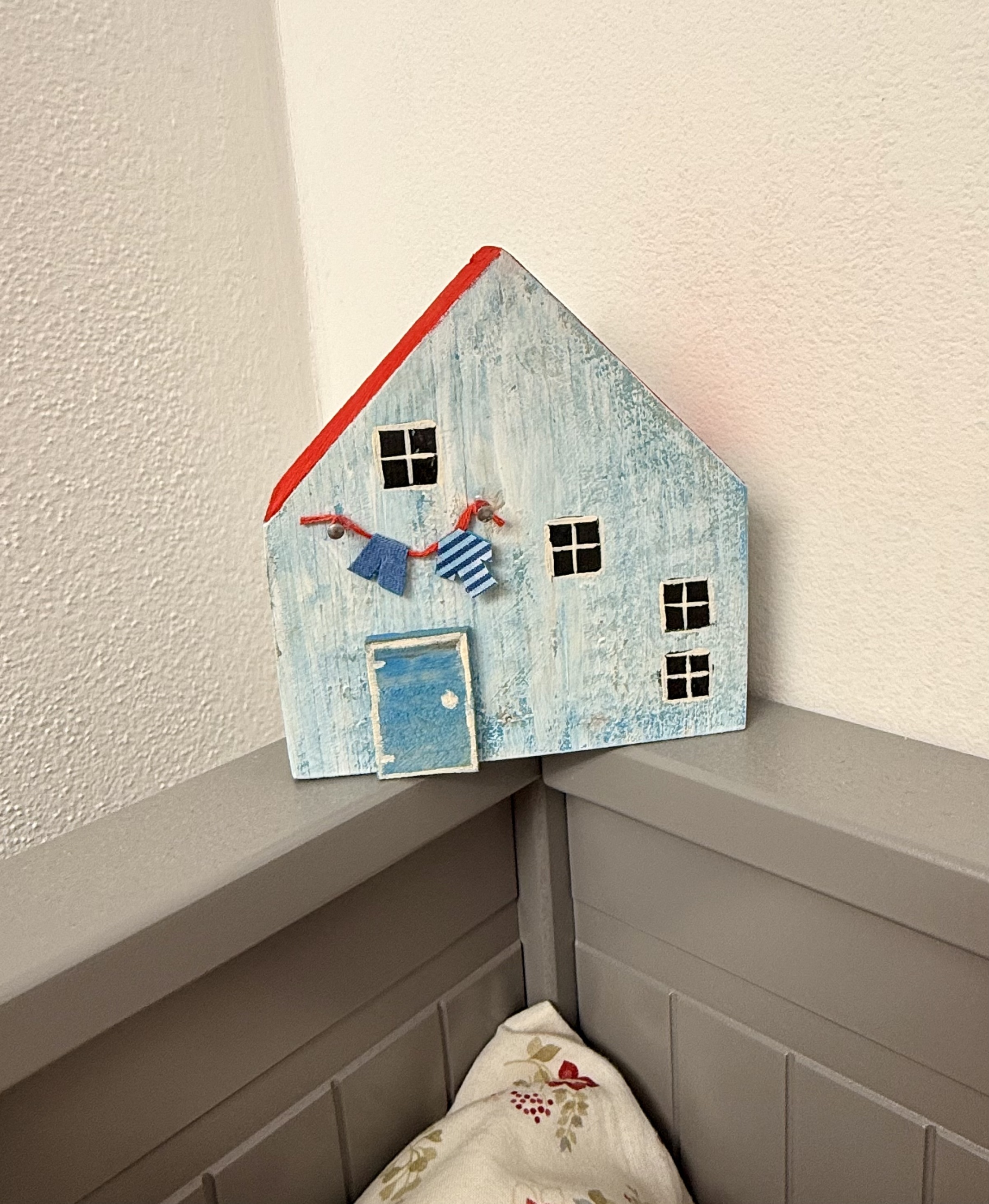 Světle modrý dřevěný domeček s červenou střechou