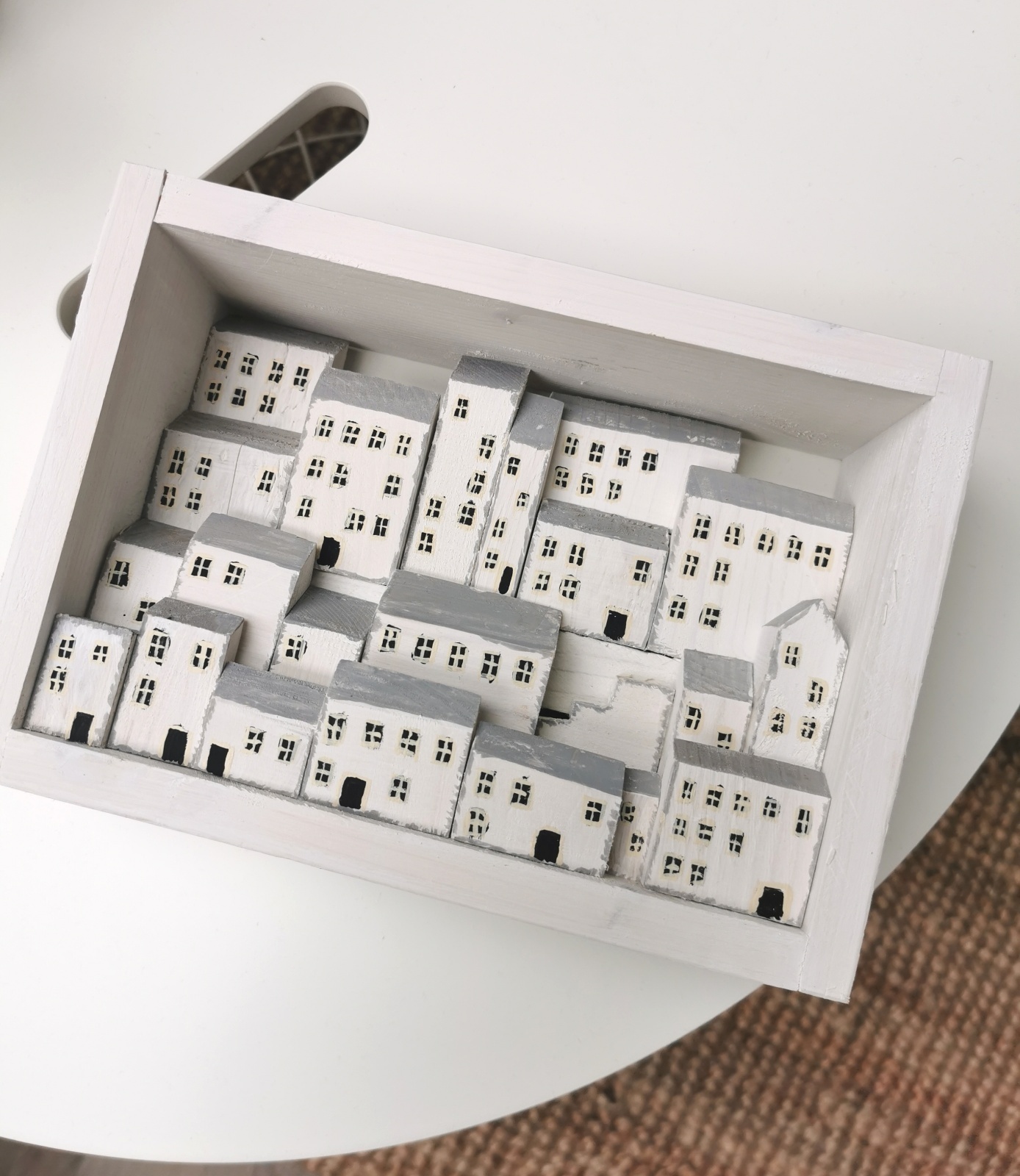 Dřevěný obrázek plný bílých domků s hlubokou perspektivou