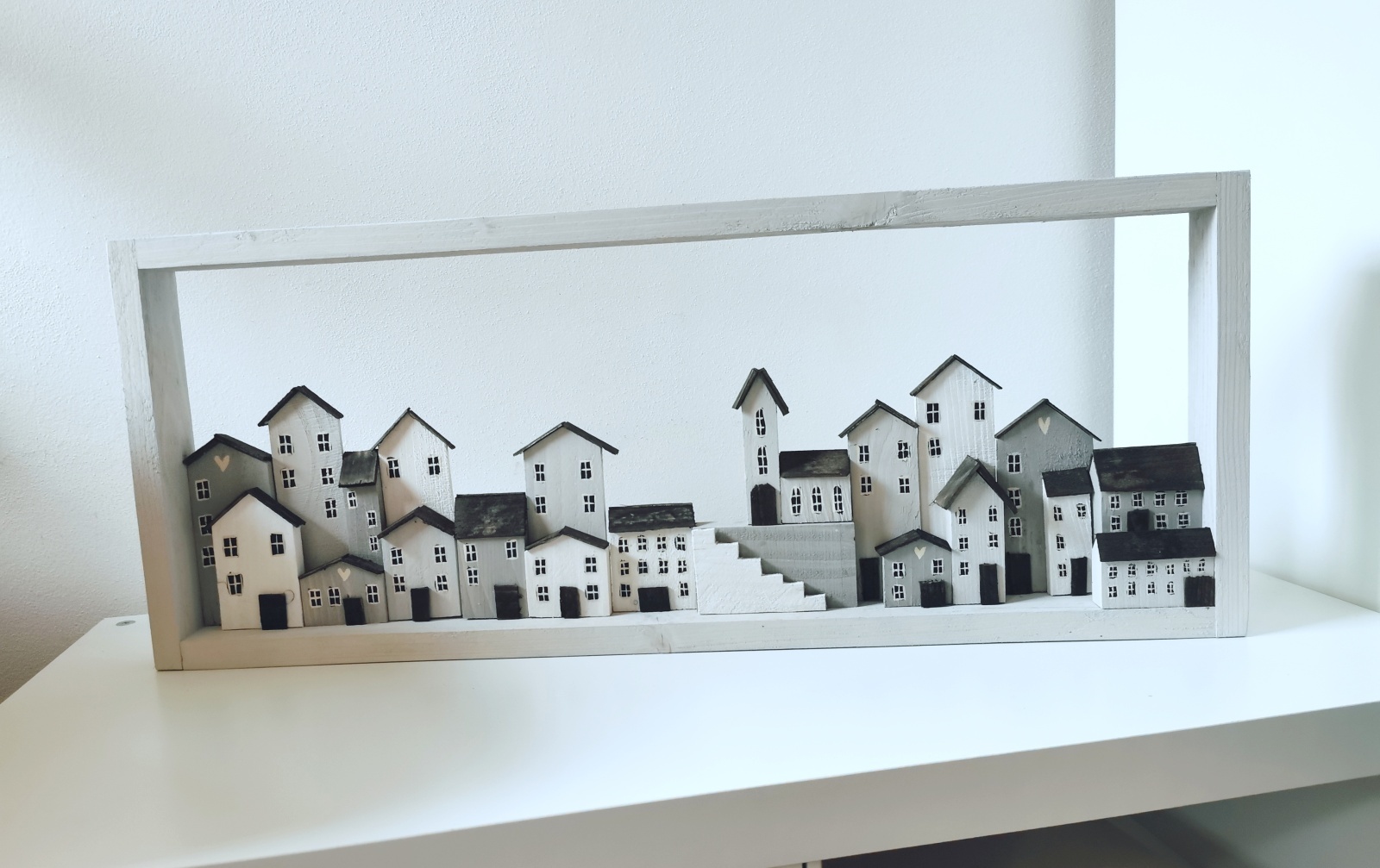 Dřevěný obraz v bílé barvě se spoustou domečků