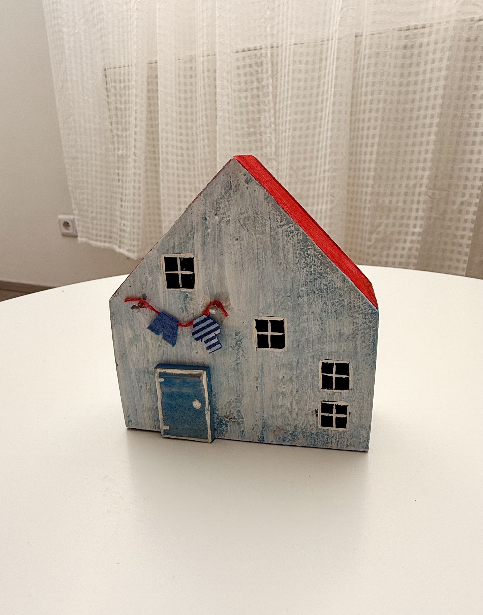 Světle modrý dřevěný domeček s červenou střechou