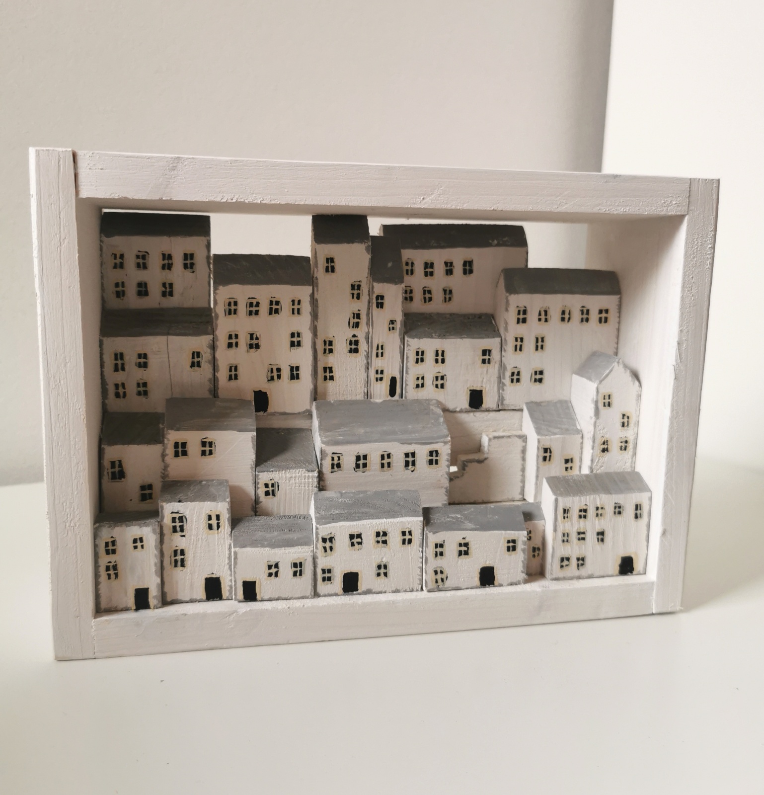 Dřevěný obrázek plný bílých domků s hlubokou perspektivou
