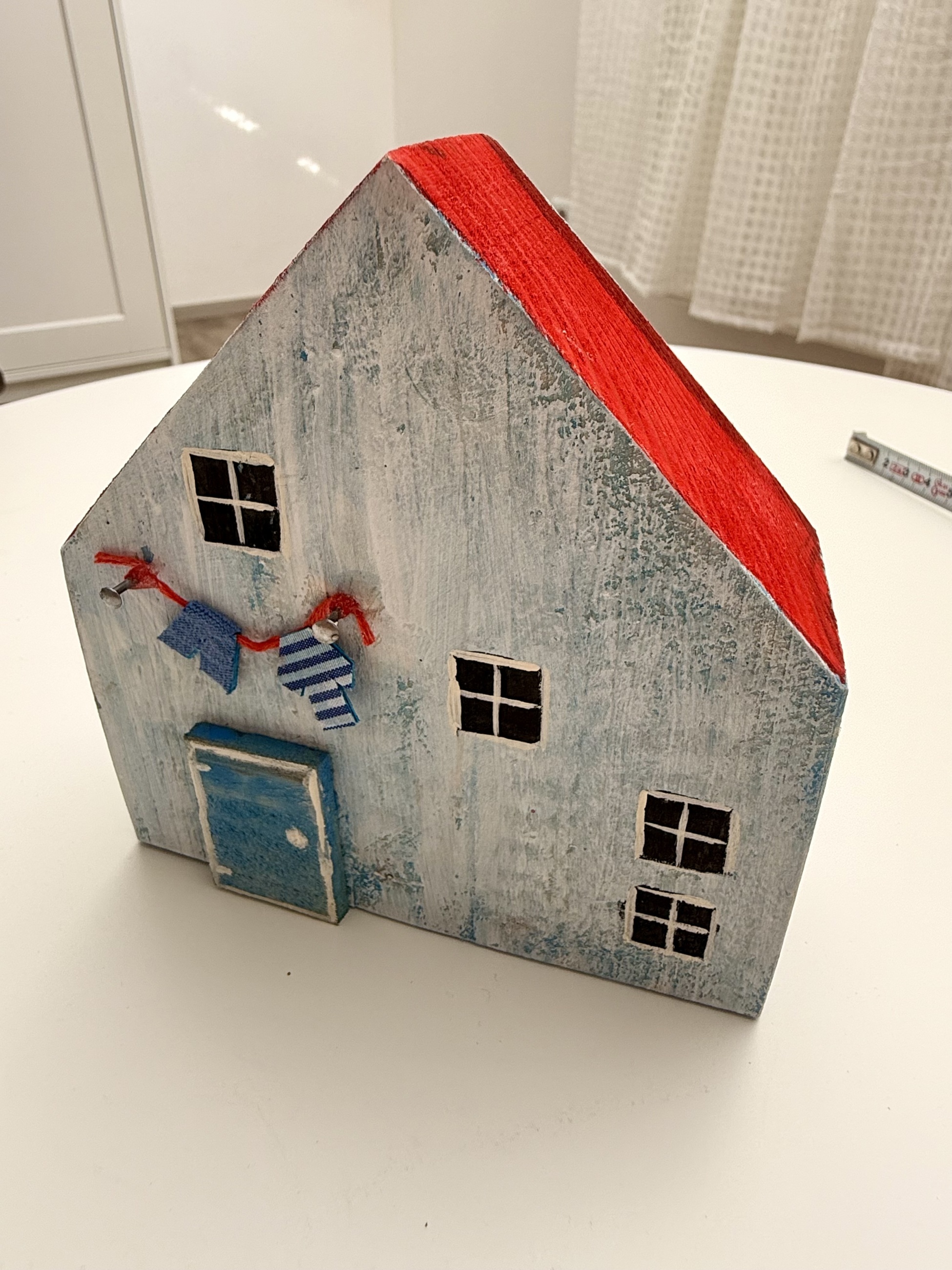 Světle modrý dřevěný domeček s červenou střechou