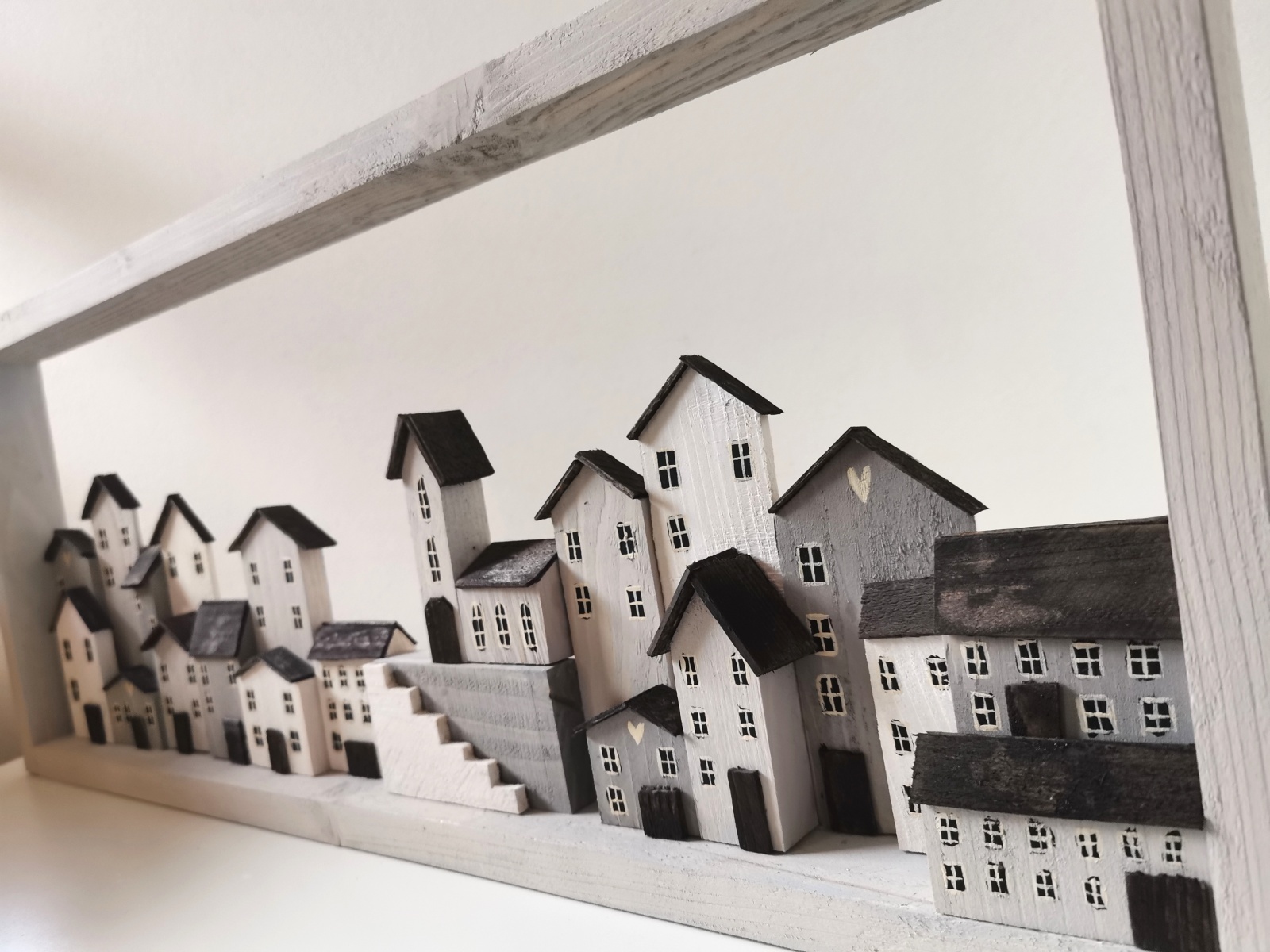 Dřevěný obraz v bílé barvě se spoustou domečků