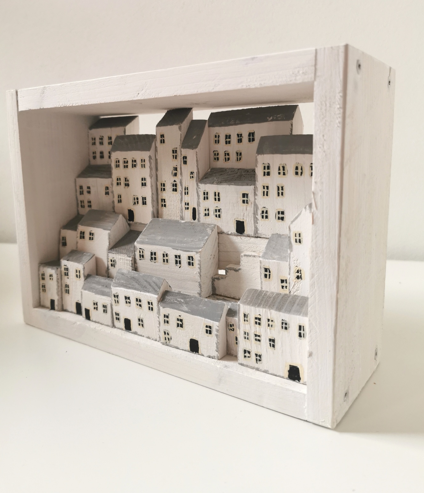 Dřevěný obrázek plný bílých domků s hlubokou perspektivou