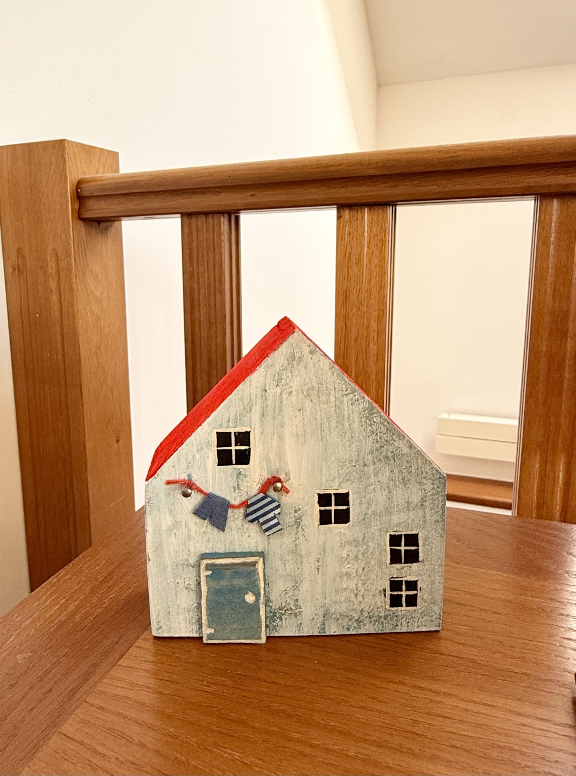 Světle modrý dřevěný domeček s červenou střechou