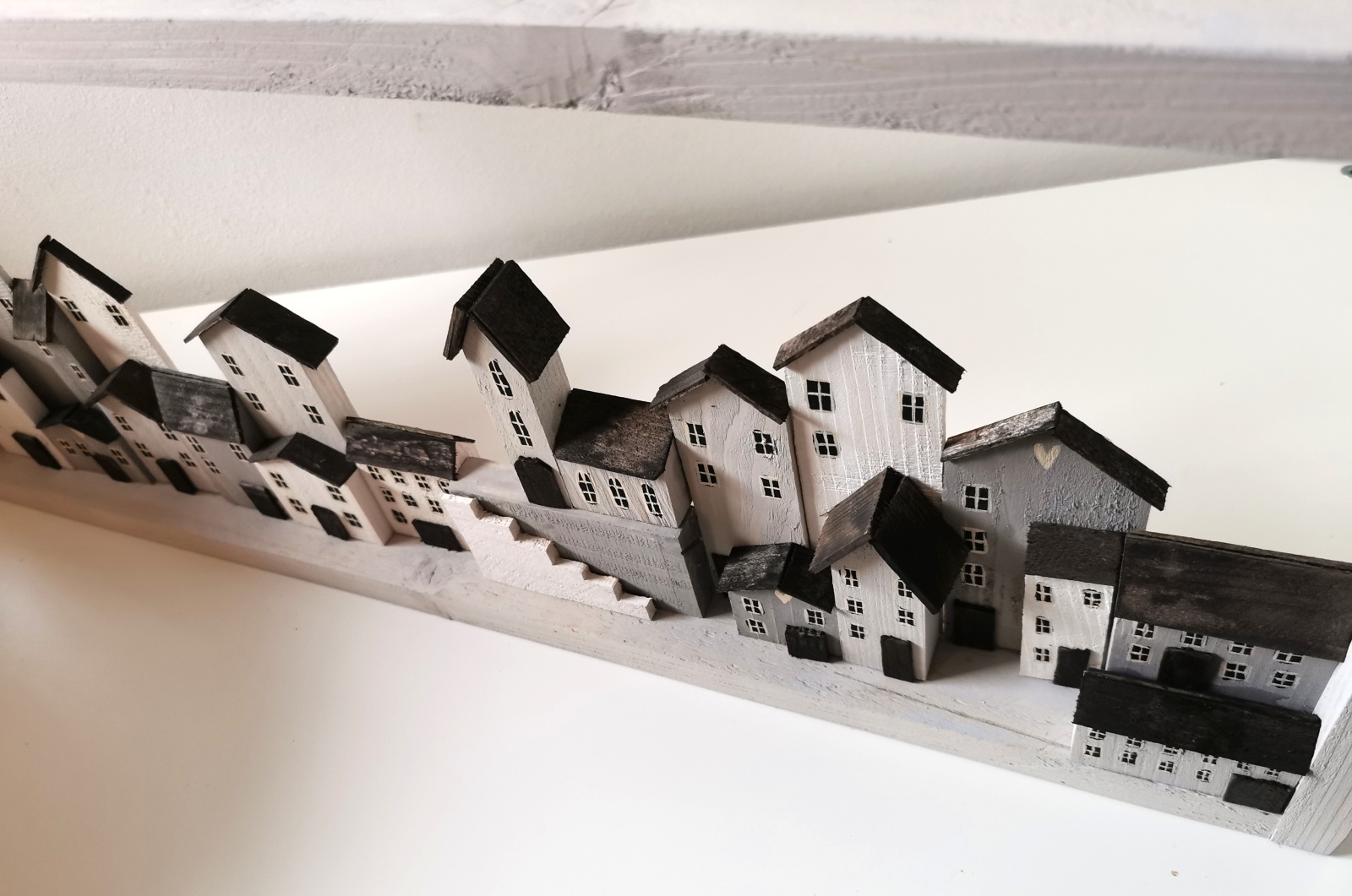 Dřevěný obraz v bílé barvě se spoustou domečků