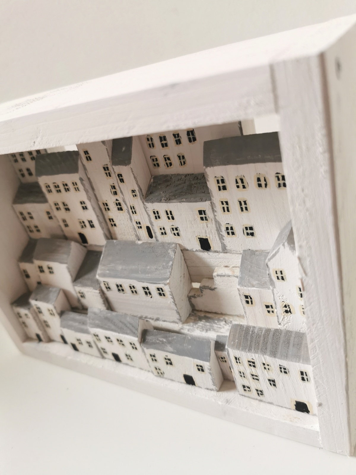 Dřevěný obrázek plný bílých domků s hlubokou perspektivou