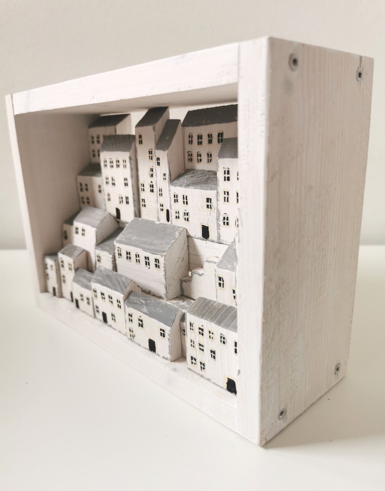 Dřevěný obrázek plný bílých domků s hlubokou perspektivou